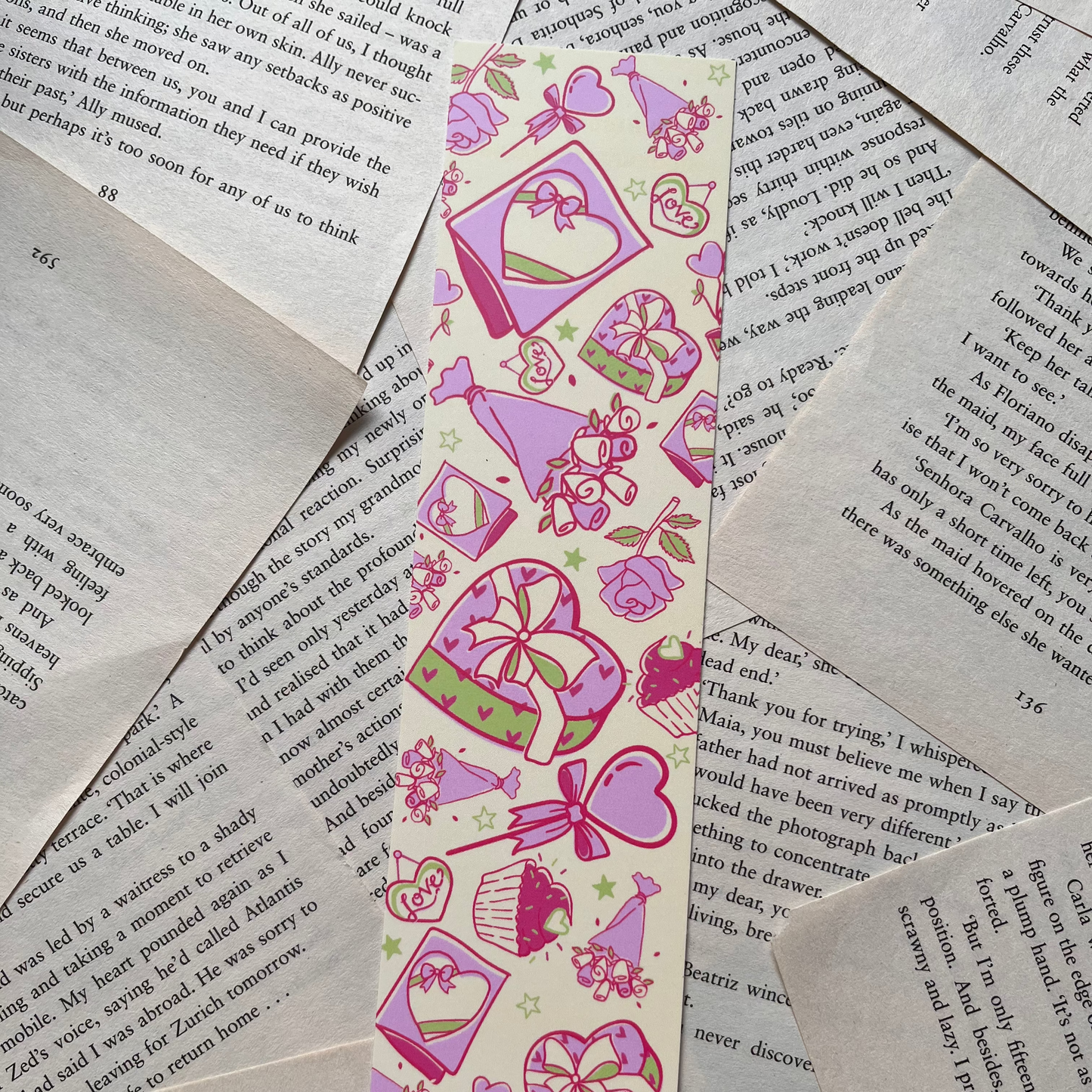Decorative bookmark with pink and purple designs on a pile of books