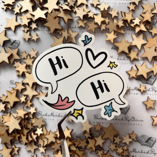 A vinyl sticker with a design consisting of two speech bubbles saying 'Hi' each other, accompanied by various simple drawings like hearts and leaves, placed on a background with multiple wooden stars.