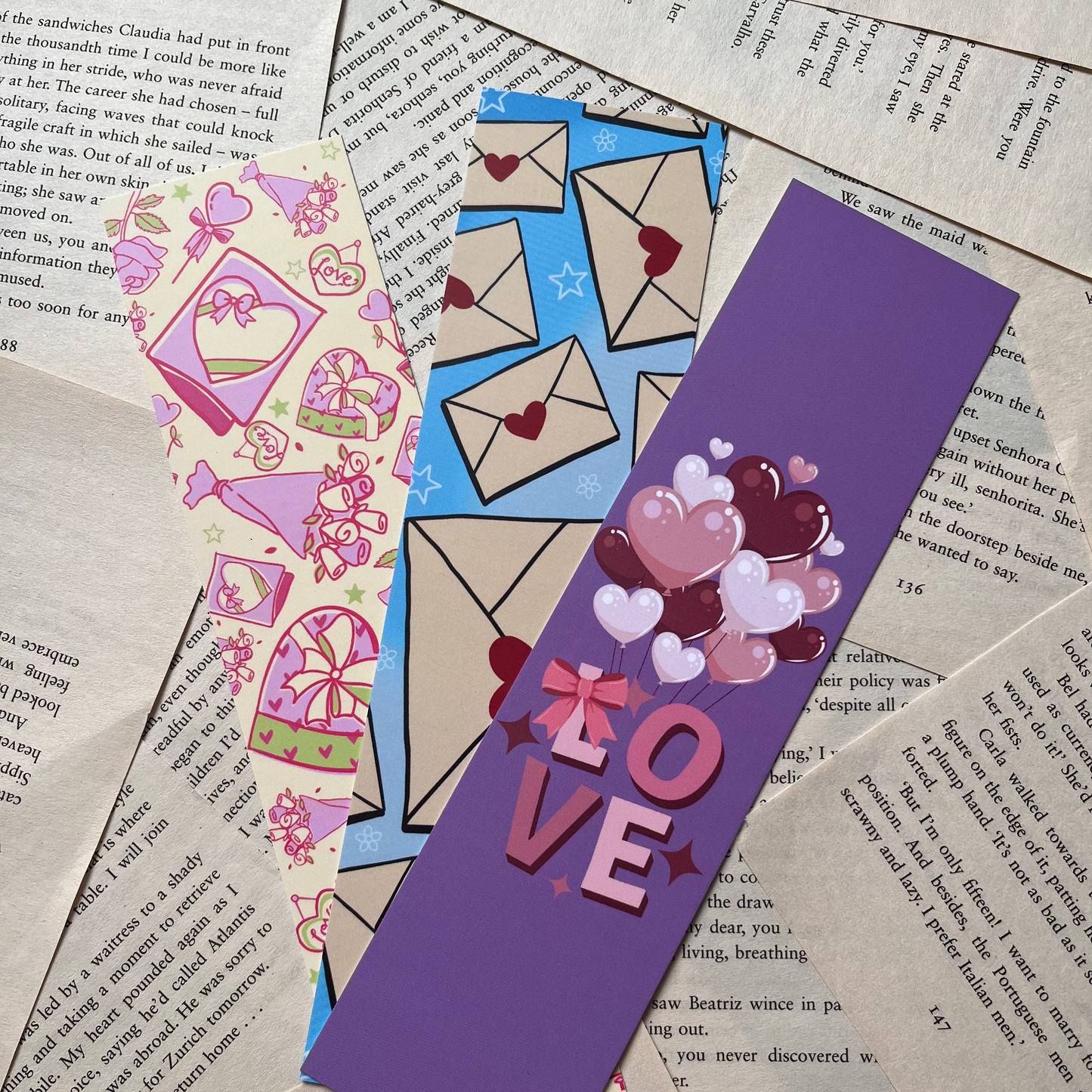 Colorful bookmarks with heart designs and the word 'LOVE' on a textured paper background.