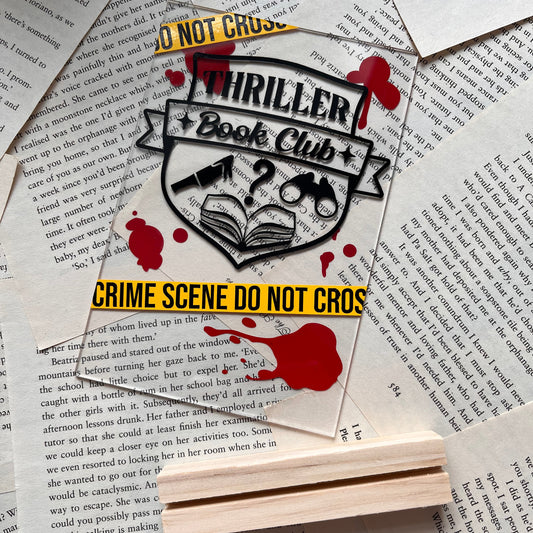 Thriller themed acrylic shelf decor with wooden stand lying flat on book pages
Text reads “thriller book club” and “crime scene do not cross” 