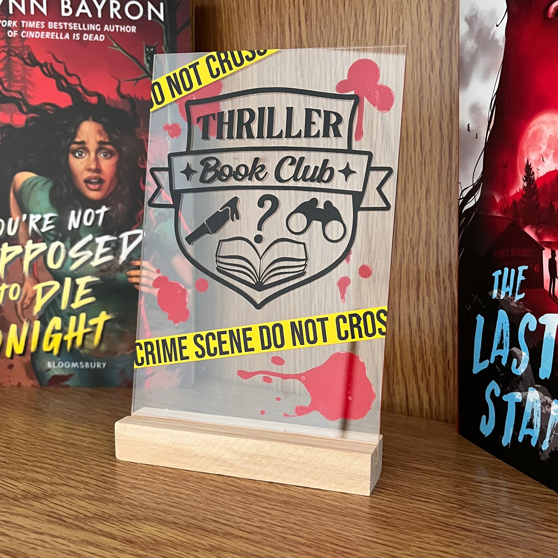 Thriller book club shelf sign with wooden stand on a bookshelf with books
