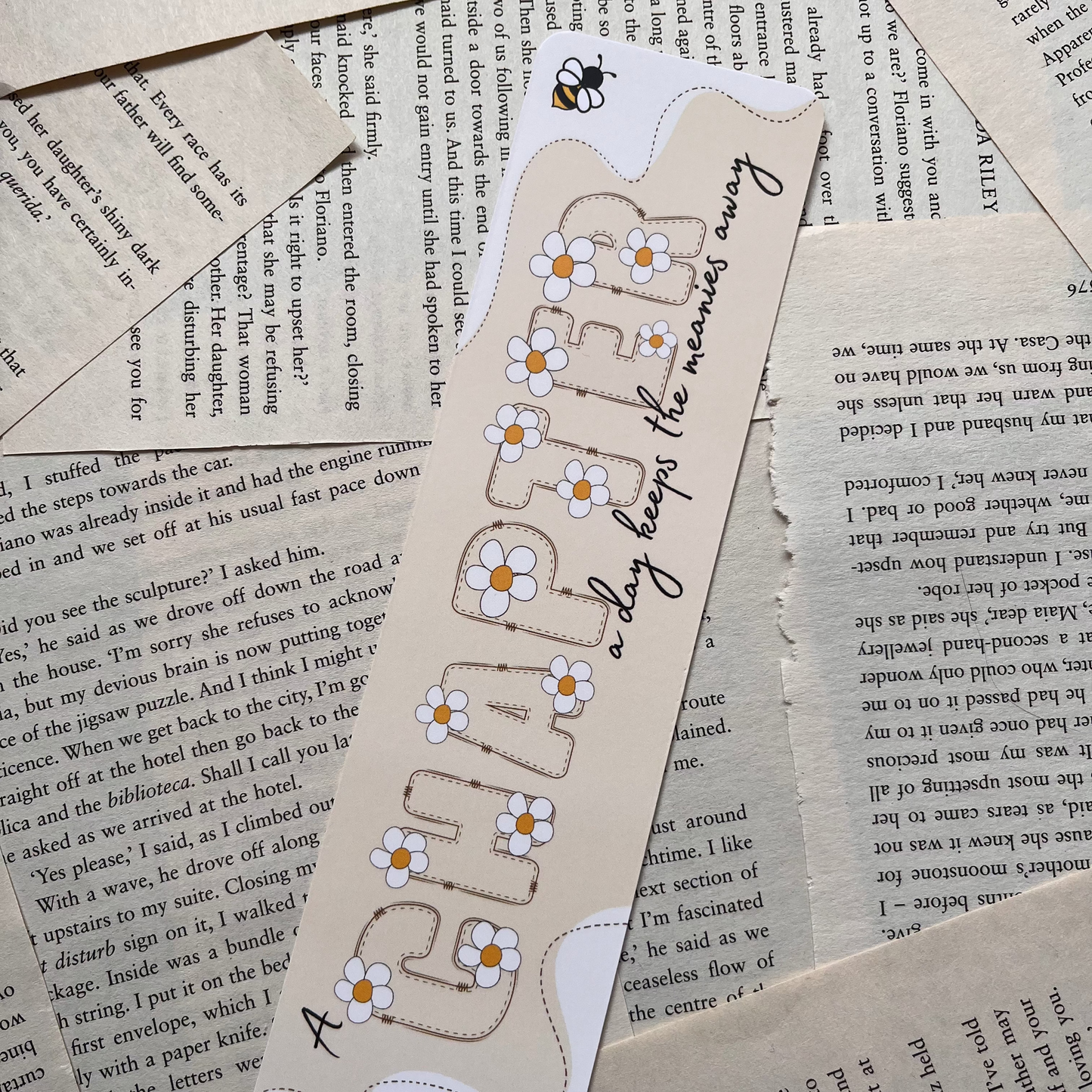 Bookmark lay on book pages. cream coloured Bookmark reads "a chapter a day keeps the meanies away"