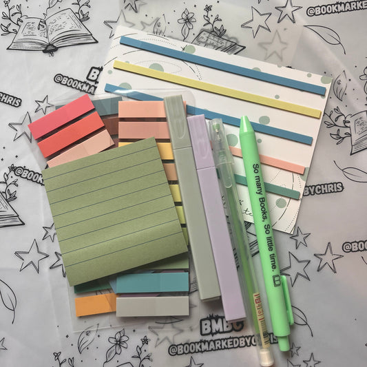 various annotation supplies for booklovers arrange on branded paper. Photo shows annotation tabs, pens and post-it notes