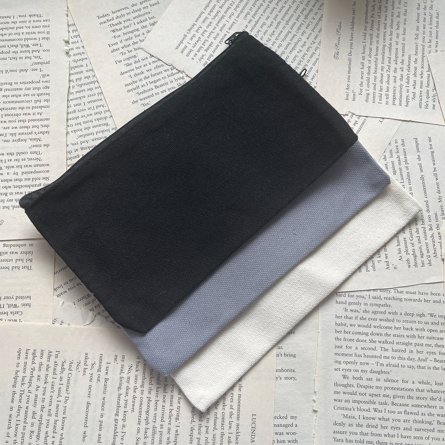 Black, grey, cream pencil cases on top of printed pages