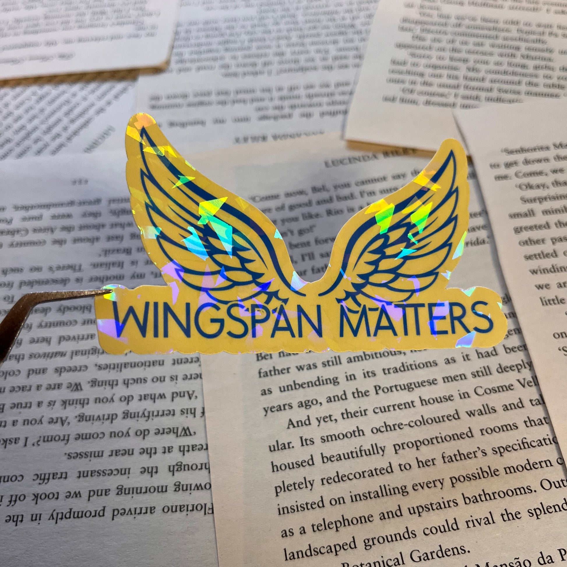 Gold 'Wingspan Matters' sticker on an open book